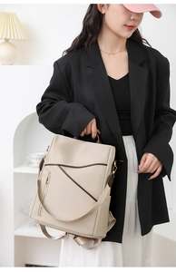 Detail of minimalist beige nylon backpack with brown trim and adjustable shoulder straps