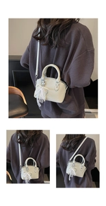Detail of lychee pattern bucket bag with lace and pearl charm on gray sweater