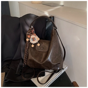 Gros plan du sac à dos en cuir marron vintage avec porte-clés peluche sur un livre