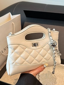 Sac à bandoulière blanc matelassé avec chaîne argentée et fermoir en métal en main