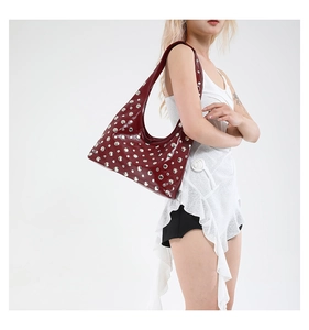 Detailed view of dark red leather shoulder bag decorated with shiny silver metal studs.