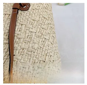 Close-up of hand-woven beige straw texture with brown leather strap and white stitching