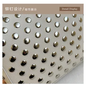 Close-up of white lychee leather texture with silver metal rivets on shoulder bag