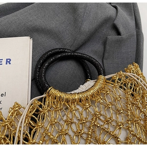 Detailaufnahme der goldenen geflochtenen Netztasche mit schwarzen runden strukturierten Griffen