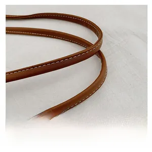 Detail of brown leather strap with decorative white stitching on a straw basket bag