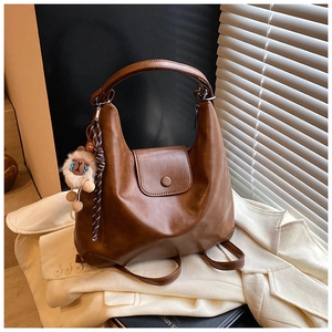 Détail du sac en cuir souple marron avec breloque lion et cordon tressé déco