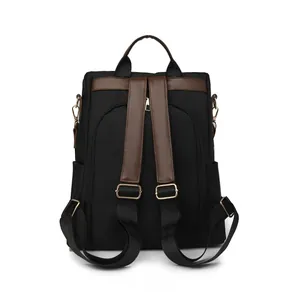 Back view of a large black nylon backpack with brown leather straps and anti-theft zipper