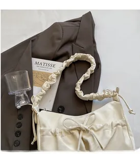 Dettaglio borsa a tracolla color crema con tracolla arricciata e fiocco decorativo fine