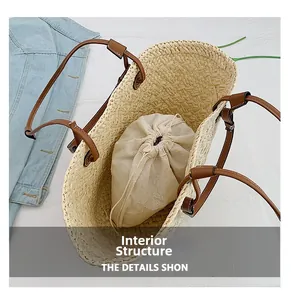 Detail view of woven straw tote bag featuring brown leather handles and drawstring inner pouch