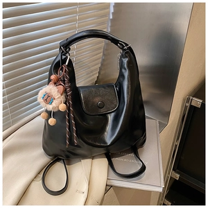 Détail du sac à dos en cuir noir avec rabat et pendentif mouton en peluche doux