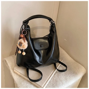 Détail du sac hobo en cuir noir souple avec charm mouton mignon sur tissu blanc