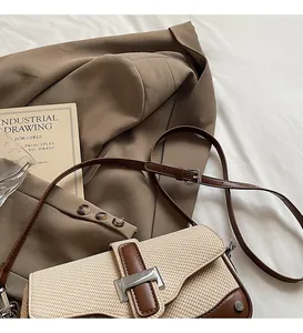 Detail view of woven patchwork shoulder bag with leather trim on a brown blazer