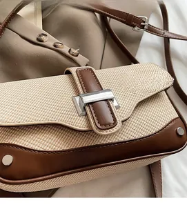 Detail of color-block woven shoulder bag featuring brown leather trim and metal buckle