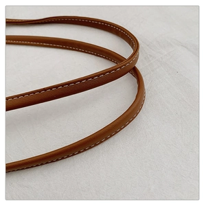 Detailed macro view of brown leather handle with premium lychee grain and white stitching