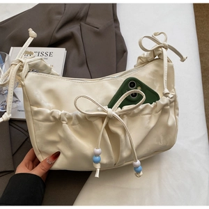 Dettaglio borsa a tracolla crema a pieghe con fiocco a coulisse e perline blu
