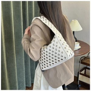 Close-up detail of white faux leather shoulder bag with silver rivet studs on surface