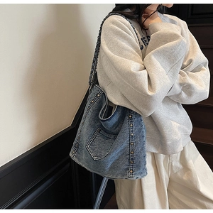 Detail of blue denim tote bag featuring vintage rivets and metal chain woven strap