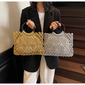 Nahaufnahme gewebter Handtaschen in Gold und Silber mit runden schwarzen Griffen