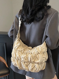 Beige pleated cloud tote bag shown on model featuring soft ruched nylon fabric