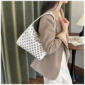 Detail of white leather shoulder bag featuring dense silver rivets and a metal zipper