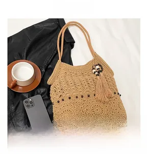 Detail view of hollow crochet pattern and wooden bead accents on the fringe woven tote bag