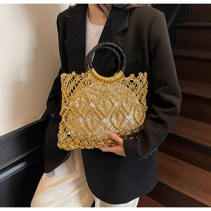 Detail der handgewebten goldenen Strandtasche mit schwarzen Griffen und Innenfutter