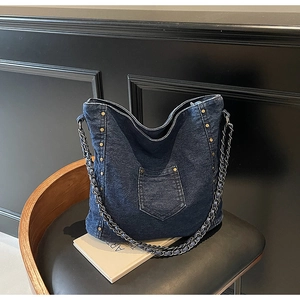 Detail of dark blue denim tote bag with gold rivets and leather-threaded chain strap