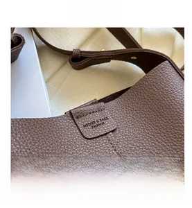 Close-up of litchi texture brown leather bucket bag with brand logo and stitching detail