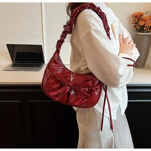 Dettaglio borsa a tracolla increspata rosso scuro con grande fiocco decorativo