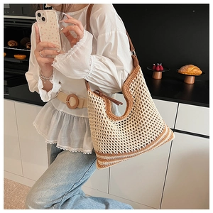 Close-up of beige hollow-out crochet woven shoulder bag with brown leather straps