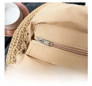 Detailed close-up of a silver metal zipper on an ivory woven straw bag with fabric lining