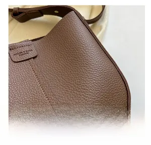 Detail view of dark brown pebbled leather texture with precise stitching on shoulder bag