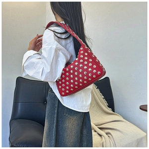 Detailed close-up of a red leather bag featuring polished silver stud embellishments