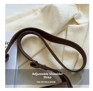 Detail of dark brown litchi pattern leather adjustable shoulder strap with gold buckle