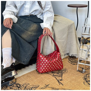 Detailed shot of a red leather shoulder bag with dense silver metal stud embellishments