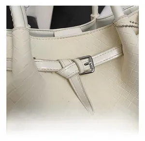 Detail showing woven leather texture and silver square buckle on cream shoulder bag