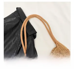 Detail of woven straw bag showing smooth cord shoulder strap and wooden bead accents