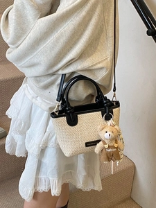 Borsa a secchiello minimalista in paglia beige con finiture in PU nero e ciondolo a orsetto