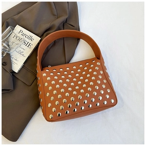 Detail of silver rivets on caramel leather shoulder bag with a vintage biker style