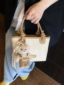 Borsa da spiaggia minimalista in paglia beige con manici marroni e ciondolo orsetto