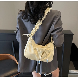 Borsa a spalla arricciata giallo crema con fiocco e perline indossata da modella