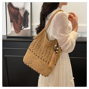 Detail of bohemian crochet straw bag featuring tassel beads and hollow weave texture