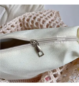 Detalle de cremallera metálica plateada en bolso de lona crema con fondo de textura tejida