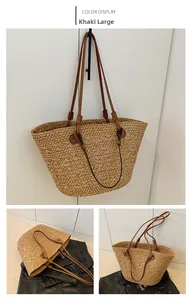 Detail of khaki straw tote bag featuring brown leather shoulder straps and woven texture