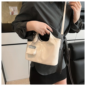 Close-up of glossy beige handbag featuring a mini decorative pouch and a shiny leather finish