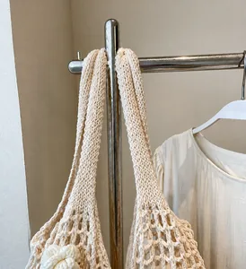 Detail einer beigen Häkeltasche mit hohlem Maschendesign und robustem Schultergurt-Muster