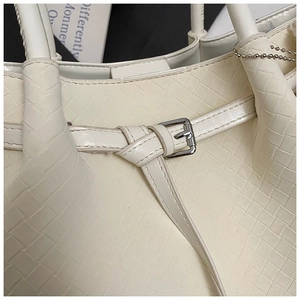 Close-up of off-white woven leather texture and silver buckle detail on bucket bag