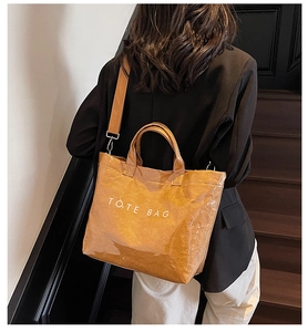 Model showing a caramel tote bag made of Tyvek paper with waterproof coating and shoulder strap