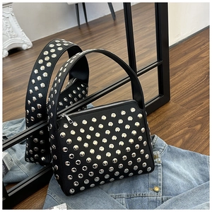 Close-up of black pebbled leather handbag with silver stud rivets and top handle detail