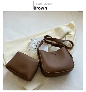 Brown lychee leather hobo bag detail with matching square pouch on soft fabric